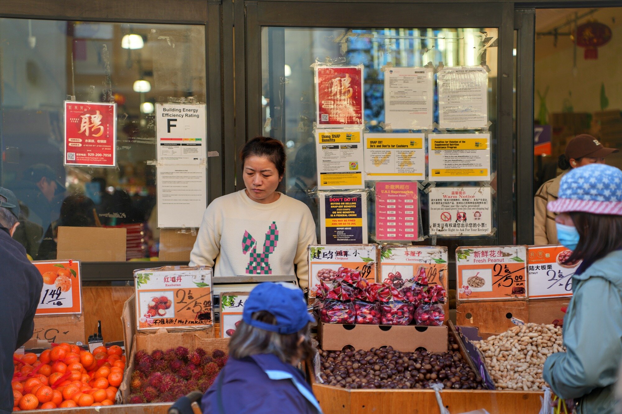A woman sells fruit from a sidewalk stand outside a supermarket. Nov. 8, 2025.