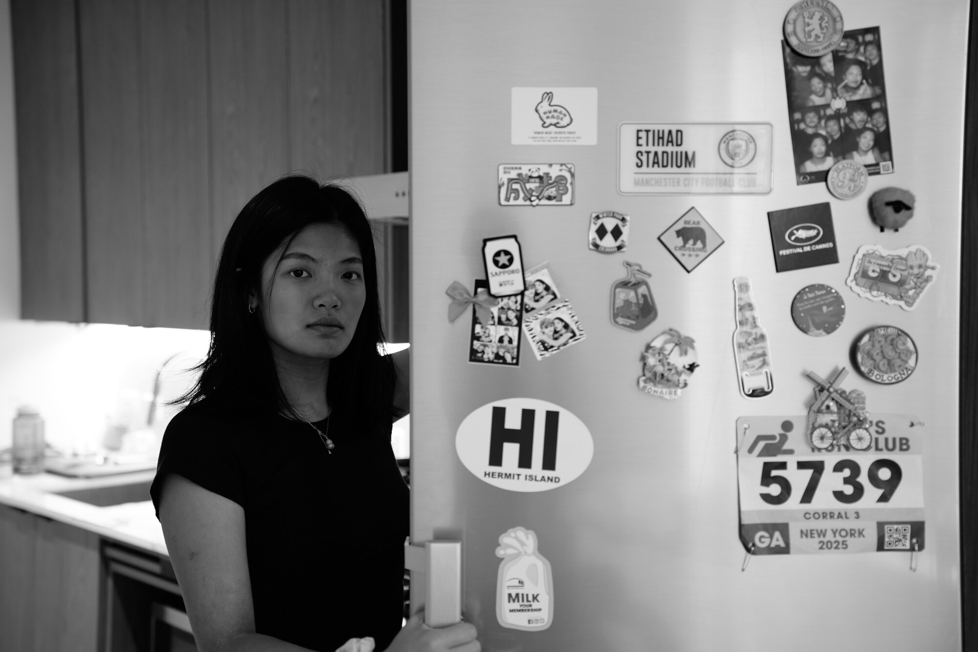 Rachel Zhong opens a refrigerator covered with magnets collected while traveling and received from friends. Nov. 22, 2025.