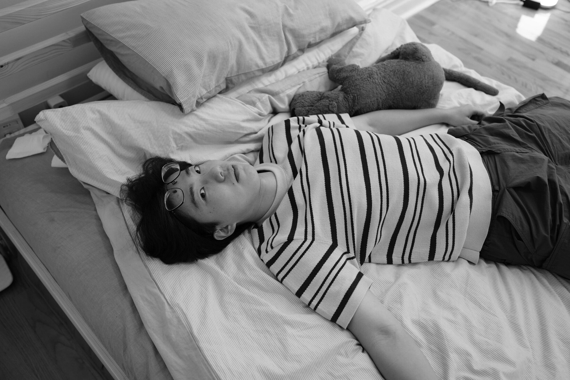 Ziyuan Yin rests on his bed beside a stuffed toy. Nov. 19, 2025.