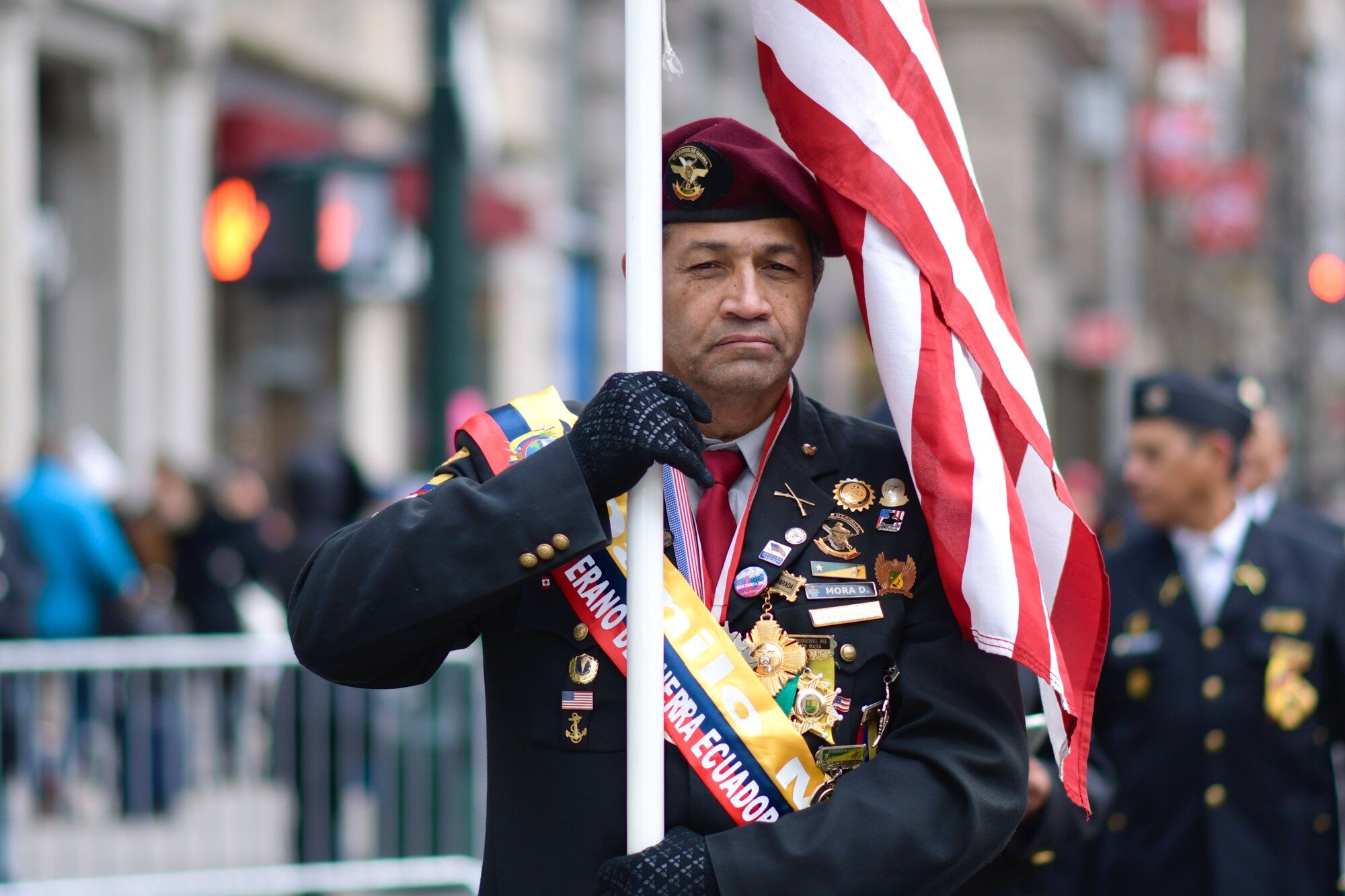A decorated Ecuadorian veteran carries the U.S. flag.